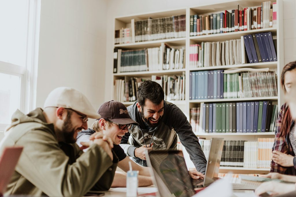 Studentai kartu dirba prie projekto universiteto bibliotekoje