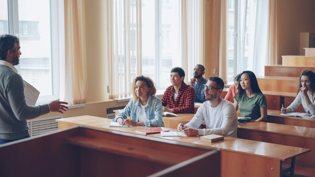 Dėstytojas veda paskaitą studentams universiteto auditorijoje